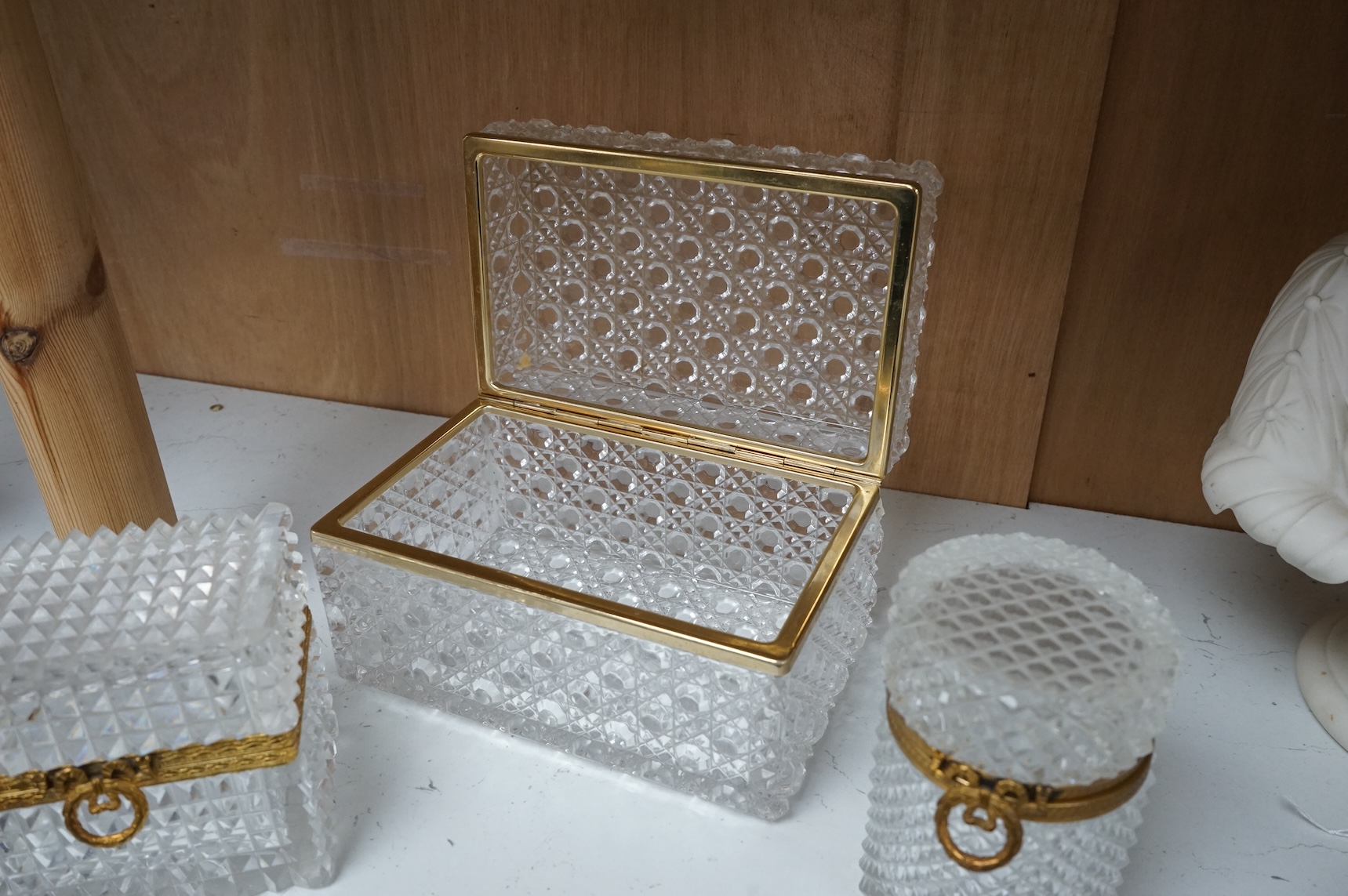 A deeply cut rectangular glass casket, a similar smaller casket and a cylindrical container, all with gilt metal mounts, largest 18cm wide x 10.5cm high.